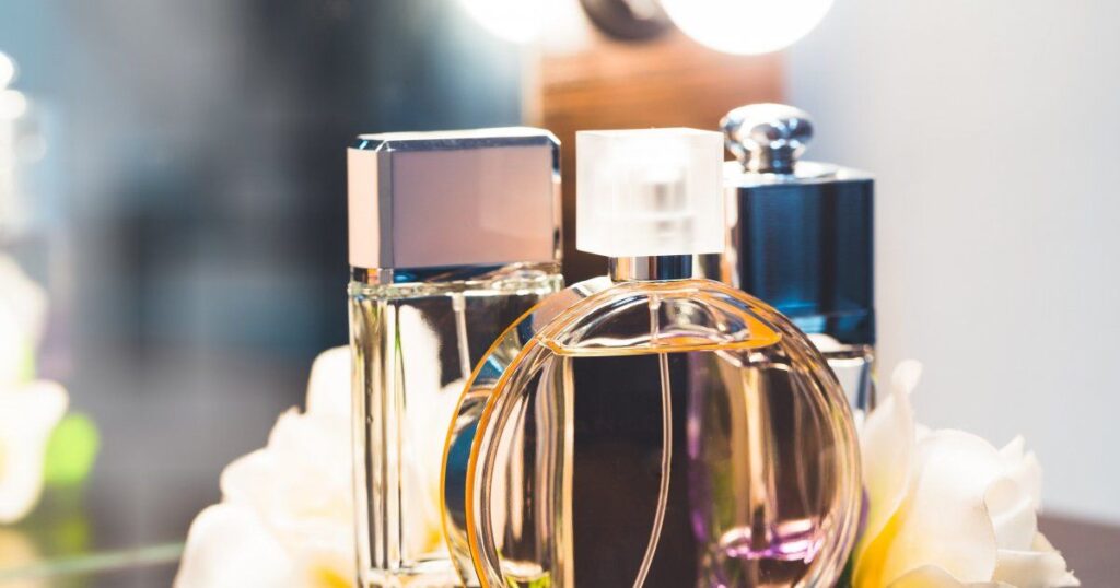 A collection of elegant perfume bottles displayed on a table, surrounded by vibrant flowers, creating a fragrant ambiance.