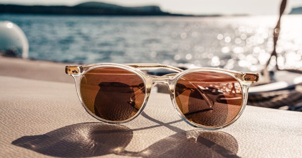 Sunglasses with glasses resting on a boat, illuminated by the sun shining brightly overhead.